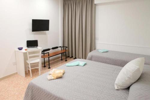 um quarto de hotel com duas camas e uma secretária com um computador em B&B Maestra Giovanna em Pompeia
