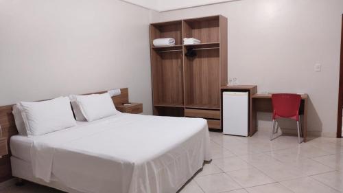 a bedroom with a bed and a desk and a red chair at Hotel Mais in Macapá