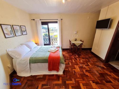 a bedroom with a bed and a table and a window at Studio Home Office - Nova Petrópolis in Nova Petrópolis