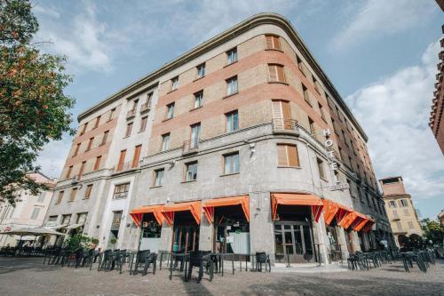 a large brick building with tables and chairs in front of it at Hotel Impero in Cremona