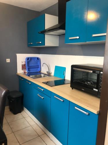 La cuisine est équipée de placards bleus, d'un évier et d'un four micro-ondes. dans l'établissement studio de la gare, à Vesoul