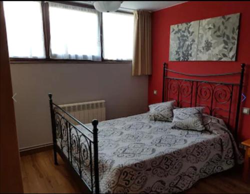 1 dormitorio con 1 cama con paredes y ventanas de color rojo en vivienda vacacional con jardín y barbacoa, en Cangas de Onís