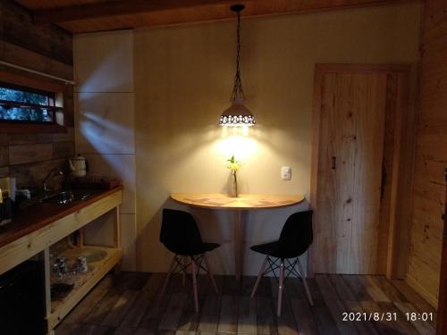 eine Küche mit einem Tisch mit Stühlen und einer Lampe in der Unterkunft Rancho do Xaxim - Gramado in Gramado