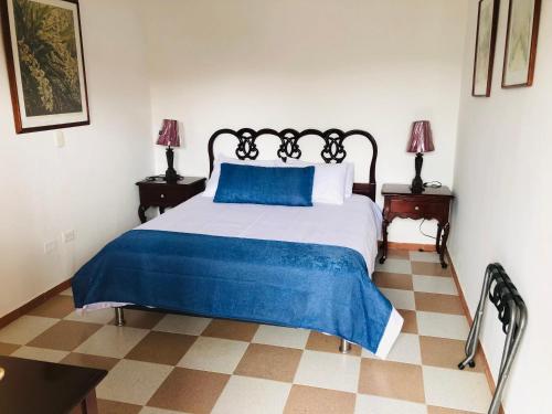 a bedroom with a bed with a blue blanket and two lamps at Castillo de Cascadas Finca Hotel in Salamina