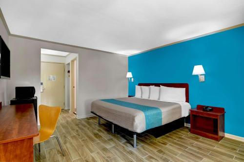 a hotel room with a bed and a blue wall at Motel 6-Norcross, GA in Norcross