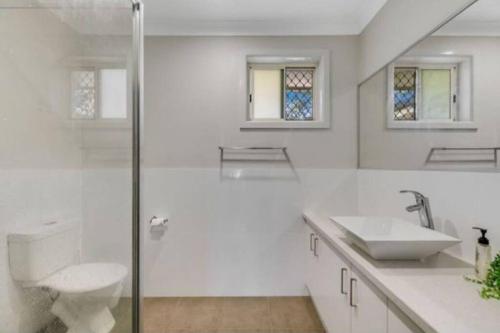 a white bathroom with a sink and a shower at Tourist Road - Studio Unit - Wi-Fi in Toowoomba