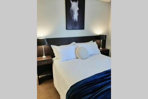 1 dormitorio con 1 cama grande con sábanas y almohadas blancas en Tourist Road - Studio Unit - Wi-Fi, en Toowoomba