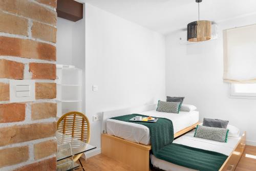 1 Schlafzimmer mit 2 Betten und Ziegelwand in der Unterkunft Victoria Place AMORA by AlohaMalaga in Málaga