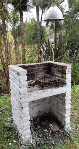 a white brick fireplace in the grass with an umbrella at Cabañas ICh in Tigre