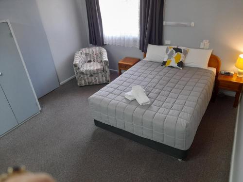 a small bedroom with a bed and a chair at Civic Motel Grafton in Grafton