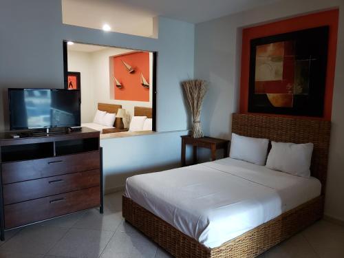 Carasol Villas y Suites Privadas في سيوداد ماديرو: غرفة نوم بسرير وتلفزيون بشاشة مسطحة