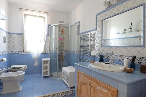 un bagno bianco e blu con servizi igienici e lavandino di SUNSET HOUSE a San Leone