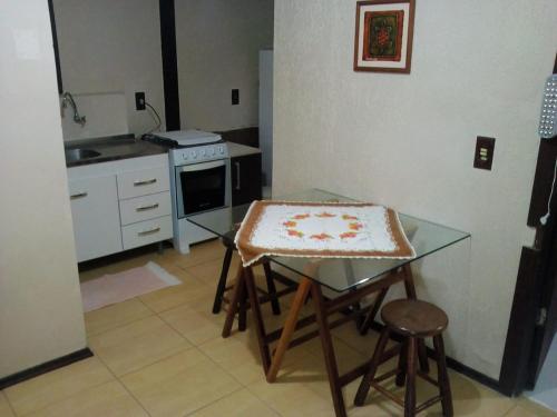 uma pequena cozinha com mesa e bancada em Nalua Guest House em Guarda do Embaú