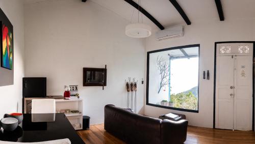 a living room with a black leather couch and a window at Dantica Cloud Forest Lodge in San Gerardo de Dota