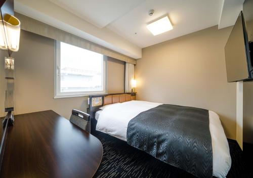 a hotel room with a bed and a flat screen tv at APA Hotel Hakata Ekimae 2Chome in Fukuoka