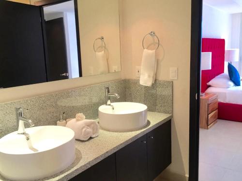 two white sinks in a bathroom with a bed at Apartamentos Grand Venetian Puerto Vallarta in Puerto Vallarta