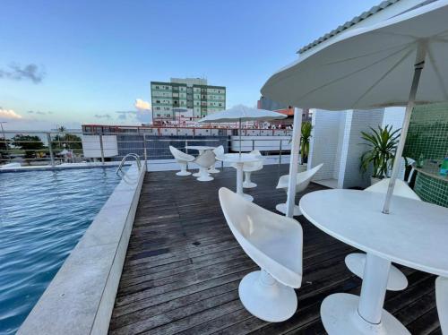 a deck with tables and chairs next to a pool at Israel Flat Tambaú in João Pessoa