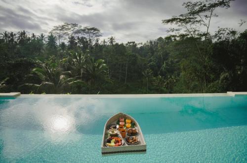 een dienblad met donuts bovenop een zwembad bij Woywoy Escape Bresela Adults Only in Tegalalang