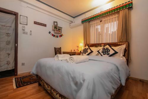 a bedroom with a bed with two towels on it at Experience Tibetan Rooms in Pokhara