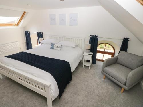 una camera con un grande letto e una sedia di Dalton Cottage a Kidwelly