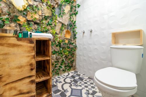 ein Badezimmer mit WC und eine Wand mit Pflanzen in der Unterkunft Ayenda Dorado Boutique in Bogotá