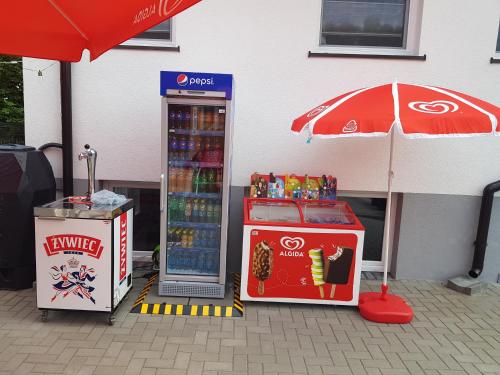 uma máquina de refrigerantes com um guarda-chuva ao lado de um refrigerador de bebidas em Siedlisko na Zaciszu Gościniec em Kąty Rybackie