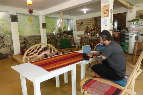 un uomo seduto a un tavolo con un portatile di Casa AHAU a San Marcos La Laguna