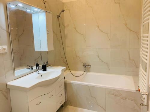ein Badezimmer mit einem Waschbecken, einer Badewanne und einem Spiegel in der Unterkunft West Residence in Budapest