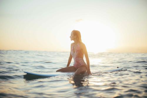 a woman sitting on a surfboard in the water at AJ Residences Apartelle in San Francisco
