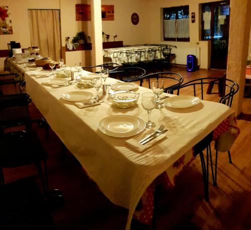 a long table with plates and wine glasses on it at Vila Maya in Băile Tuşnad