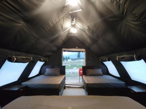 TālにあるKumrat Glamping Resortsのテント内のベッド2台、窓が備わる客室です。
