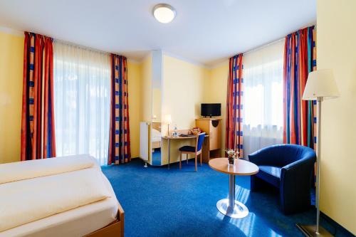 a hotel room with a bed and a chair and a table at Hotel Graf Lehndorff zur Messe in Munich