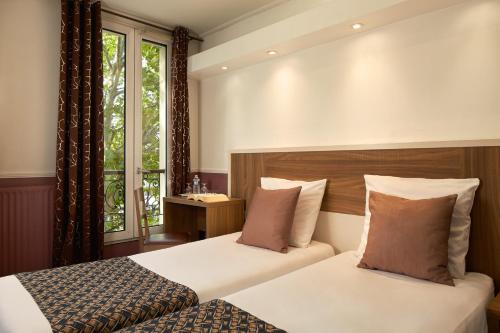 a bedroom with two beds and a window at Grand Hotel Nouvel Opera in Paris