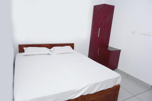 a bedroom with a white bed with a wooden headboard at THEKKUMPURAM RESIDENCY in Kondotti