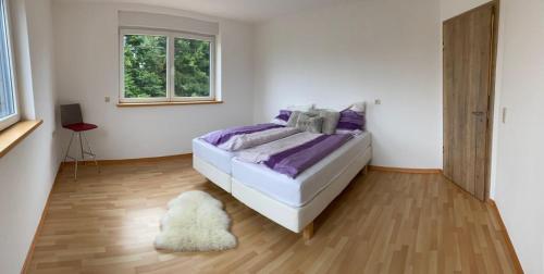 a bedroom with a bed with purple sheets and a rug at Residenz Arens in Amblève