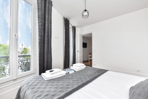 ein weißes Schlafzimmer mit einem Bett und einem Fenster in der Unterkunft CMG Menilmontant in Paris