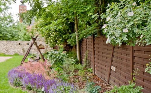 a garden with a brick fence and purple flowers at Zajazd Mat in Bełk