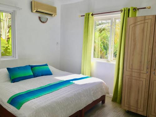 a bedroom with a bed with green curtains and a window at Beachfront Villa in a beautiful and secured complex in Flic-en-Flac