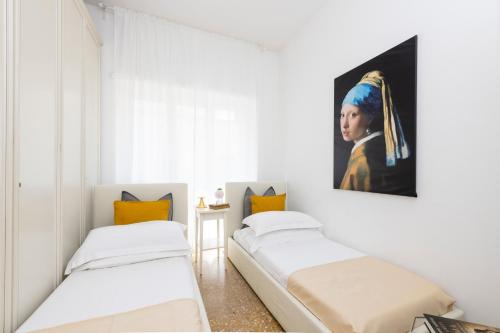 two beds in a room with a painting of a woman at Maison Clodia in Rome