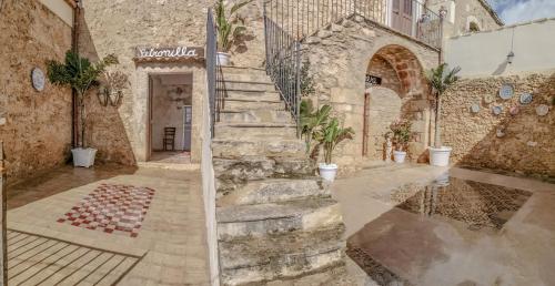 a stone building with a staircase in a courtyard at Feudo Nobile in Gela