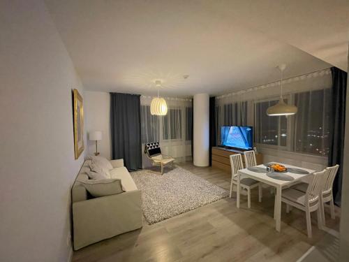 a living room with a couch and a table and a tv at 34 floor at the top of the Baltic in Klaipėda