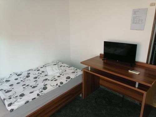 a bedroom with a bed and a desk with a television at Šulentić sobe i restoran in Virovitica