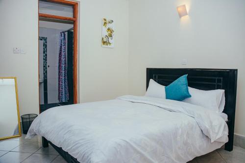 a bedroom with a large white bed with blue pillows at Elegant Art Deco Home with Free Wi-Fi, Parking, Netflix, Office Desk, Computer & Baby Cot in Ruaka in Ruaka