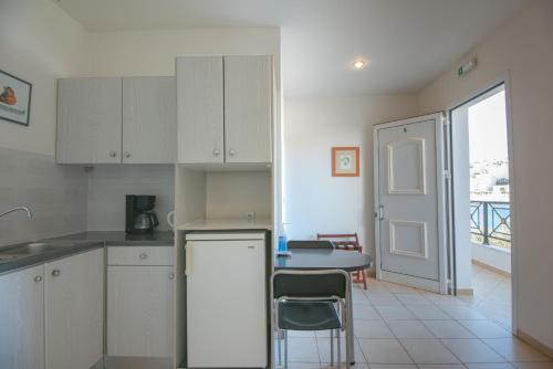 a kitchen with white cabinets and a table with chairs at Polydoros Appartments in Agios Nikolaos
