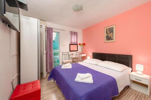 um quarto com uma cama roxa e paredes cor-de-rosa em Damira Rooms em Split