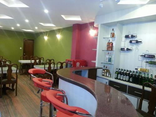 a restaurant with a bar with red stools at Hotel Pleasure Home in Kathmandu