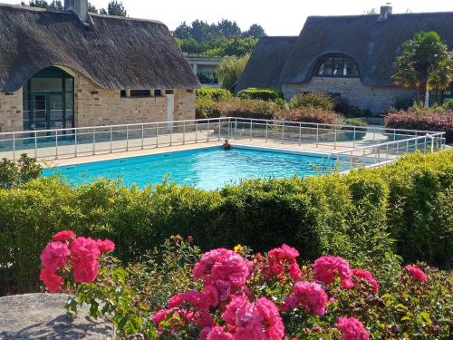 - une piscine en face d'une maison ornée de fleurs roses dans l'établissement Appartement de standing dans le Golf International de La Baule, à Saint-André-des-Eaux