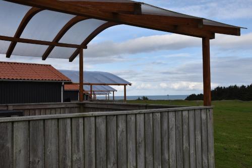 a wooden fence with a gazebo in a field at Hytteby – Hanstholm Camping – Thy Feriepark in Hanstholm