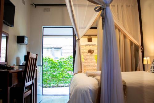 a bedroom with a bed and a door to a patio at Dzimbahwe Guest Lodge in Victoria Falls