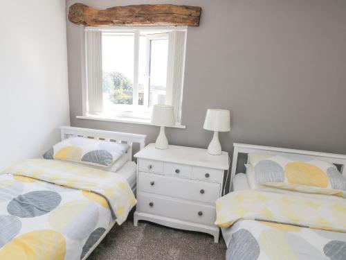 a bedroom with two twin beds and a window at Rhosydd Cottage in Llanallgo